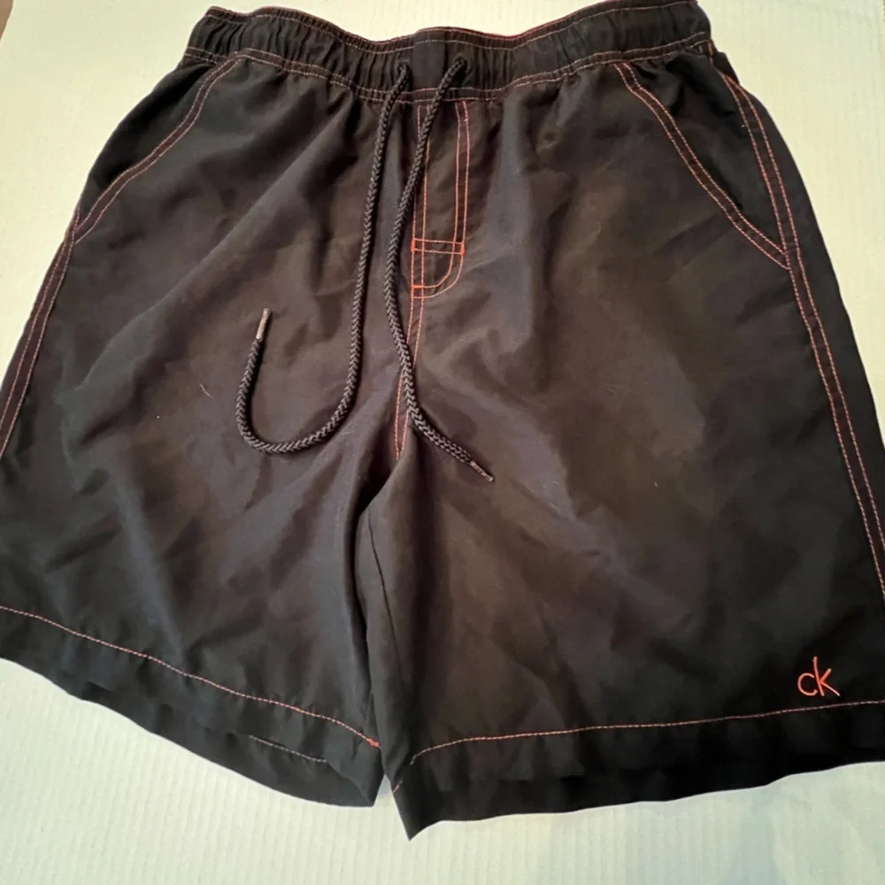 CALVIN KLEIN MENS SWIM TRUNKS. SIZE MEDIUM. BLACK WITH ORANGE STITCHING